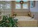 Garden tub featuring glass block accents, garden view, and tiled walls at 410 Fitzgerald Ln, Fayetteville, GA 30215