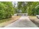 Scenic view of a white brick home nestled among lush trees with a long driveway at 703 Alvis Ln, Norcross, GA 30093