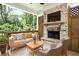 Covered outdoor patio featuring a brick fireplace and comfortable seating with wooded views at 1300 Winfair Ne Ln, Brookhaven, GA 30329