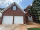 Charming red brick two-story home featuring a two-car garage, black shutters, and manicured lawn at 330 Kentwood Springs Dr, Hampton, GA 30228