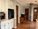 Kitchen featuring wooden floors, white cabinets, and black appliances at 4506 Town Crier Sw Rd, Lilburn, GA 30047