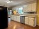 Traditional kitchen featuring wooden floors, white cabinets, and stainless steel appliances at 4506 Town Crier Sw Rd, Lilburn, GA 30047