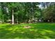 Spacious backyard with a stone fire pit surrounded by lush greenery and mature trees at 5290 River Mill Cir, Marietta, GA 30068