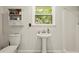 Clean bathroom features a pedestal sink, a cabinet for storage, and a window to the backyard at 5290 River Mill Cir, Marietta, GA 30068
