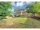 A spacious backyard featuring a well-manicured lawn, mature trees, and a wooden deck at 10400 Groomsbridge Rd, Alpharetta, GA 30022