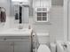 Neutral bathroom featuring a single sink vanity and standard toilet with white subway tile and grey walls at 10400 Groomsbridge Rd, Alpharetta, GA 30022