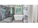 Modern bathroom featuring a glass shower, a free standing tub, and an arched window with shutters at 10400 Groomsbridge Rd, Alpharetta, GA 30022