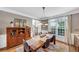 Formal dining room features a wooden table, cabinet, overhead lighting and a large window providing natural light at 10400 Groomsbridge Rd, Alpharetta, GA 30022