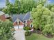Charming brick home with a well-manicured lawn, mature trees, and a three-car garage at 10400 Groomsbridge Rd, Alpharetta, GA 30022