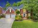Charming two-story red brick home boasts a three-car garage and lush landscaping at 10400 Groomsbridge Rd, Alpharetta, GA 30022