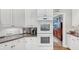 Close up view of white cabinets, granite countertops and stainless appliances with a double oven at 10400 Groomsbridge Rd, Alpharetta, GA 30022