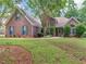 Charming brick home with manicured lawn, complemented by lush landscaping and mature trees at 1585 Lake Dow Rd, Mcdonough, GA 30252