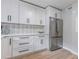Modern kitchen with white cabinetry, stainless steel refrigerator, stylish backsplash, and light wood flooring at 2012 Variations Ne Dr, Atlanta, GA 30329