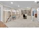 Large bonus room with built-in bookcases, desk area, neutral carpet, and stairs leading to the main floor at 1311 Cobblemill Nw Way, Kennesaw, GA 30152