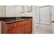 Bathroom vanity with granite countertop, warm cabinetry and view to the shower at 2921 Lenox Rd # 308, Atlanta, GA 30324