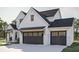 Angle view of a two-car garage with carriage doors, black trim windows, and a white brick facade at 3629 Centerville Rosebud Rd, Snellville, GA 30039