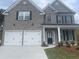 Two-story home with gray brick, black shutters, a two-car garage, and a covered front entrance at 1678 Lacebark Elm Way Way, Lawrenceville, GA 30045