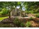 Backyard view with stone patio, sunroom, and lush landscaping at 230 Bristol Stone Ct, Johns Creek, GA 30005