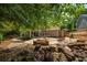 Secluded backyard with a stone patio, fire pit, lounge seating, and mature trees creates a serene outdoor retreat at 230 Bristol Stone Ct, Johns Creek, GA 30005