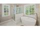 Bright bathroom featuring a glass shower with gold hardware, standalone tub, and white marble flooring at 230 Bristol Stone Ct, Johns Creek, GA 30005