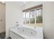 Bright bathroom featuring a jetted soaking tub under a large multi-pane window at 3032 Ross Rd, Snellville, GA 30039