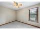 This carpeted bedroom features a ceiling fan and a view of the tree lined backyard at 3032 Ross Rd, Snellville, GA 30039