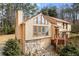 Angle view of exterior showing stone accents, garage, and wooden front stairs surrounded by mature trees and landscaping at 3032 Ross Rd, Snellville, GA 30039