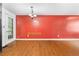 An empty dining room featuring hardwood floors, a red wall and hanging light fixture at 1822 Oriole Trl, Lithia Springs, GA 30122