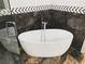 A stylish bathroom with a modern free standing tub, marble floors, and geometric tile accents at 664 Florence Nw Pl, Atlanta, GA 30318