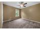 This bedroom has neutral paint, carpet, a ceiling fan and a window overlooking the front yard at 5312 Tormeal Trce, Suwanee, GA 30024