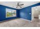 This bedroom has blue paint, carpet, a ceiling fan and a window overlooking the front yard at 5312 Tormeal Trce, Suwanee, GA 30024