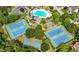 Aerial view highlighting community amenities: a pool, tennis courts, and a basketball court surrounded by trees at 5312 Tormeal Trce, Suwanee, GA 30024