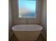 Elegant soaking tub with a modern faucet under a window at 246 Crabapple Rd, Mcdonough, GA 30253