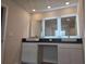 Bathroom vanity featuring double sinks, dark countertops, and lighted mirrors at 246 Crabapple Rd, Mcdonough, GA 30253