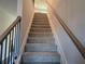 Carpeted staircase with metal balusters and wood handrail at 246 Crabapple Rd, Mcdonough, GA 30253