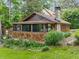 Cozy bungalow with wood shingles, stone chimney, and screened porch surrounded by greenery at 4624 Park Dr, Pine Lake, GA 30072