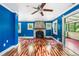 Bright living room with blue walls, hardwood floors, a stone fireplace, and a ceiling fan at 4624 Park Dr, Pine Lake, GA 30072