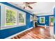 Bright living room featuring hardwood floors, blue walls, a stone fireplace, and large windows at 4624 Park Dr, Pine Lake, GA 30072
