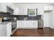 Bright kitchen with stainless steel appliances, white cabinets, dark backsplash and wood-look flooring at 1712 Evans Sw Dr, Atlanta, GA 30310