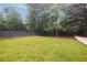 Wide backyard featuring a green lawn, tall trees, and a black wooden fence offering privacy and natural beauty at 4132 Carmain Ne Dr, Atlanta, GA 30342