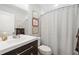 Modern bathroom with a dark vanity, framed pictures, toilet, and shower with a black and white curtain at 2572 Beverly Hills Drive Dr, Chamblee, GA 30341