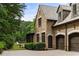 Brick house featuring attached two car garage, arched doorway, professional landscaping, and a private backyard at 4560 Harris Trl, Atlanta, GA 30327