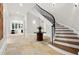 Elegant foyer with a curved staircase, stone floors, and a sophisticated table centerpiece at 4560 Harris Trl, Atlanta, GA 30327