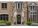 Charming front entrance with stone detailing, arched doorway, and lush landscaping, creating curb appeal at 4560 Harris Trl, Atlanta, GA 30327