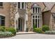 Elegant stone home with arched doorway, lush landscaping, and paved driveway, a welcoming entrance at 4560 Harris Trl, Atlanta, GA 30327