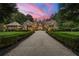 Stunning home exterior with a large driveway, lush landscaping, and warm lighting creating inviting curb appeal at 4560 Harris Trl, Atlanta, GA 30327