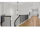 Upstairs hallway featuring hardwood floors, black metal railings, and modern light fixtures at 4560 Harris Trl, Atlanta, GA 30327