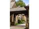 Close up of the Porte-Cochere, featuring dark wood beams, brick and stone architecture, and lush landscaping at 4560 Harris Trl, Atlanta, GA 30327