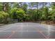 Well-maintained backyard tennis court surrounded by lush greenery and secure fencing at 4560 Harris Trl, Atlanta, GA 30327
