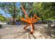 A modern art sculpture made of orange beams at the edge of a sidewalk with trees and a building in the background at 710 Oakview Rd, Decatur, GA 30030
